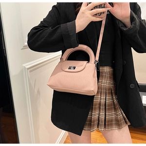 Detail of elegant striped crossbody bag in peach pink with silver metallic twist lock