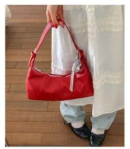 Dettaglio della borsa hobo rossa con trama a grana, zip argento e tracolla a nodo