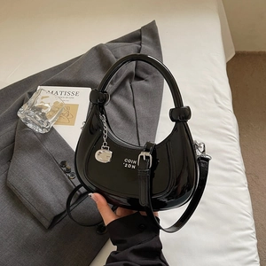 Detail of glossy black hobo bag with silver G-charm and detachable shoulder strap