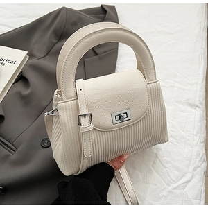 Close-up of cream white pleated shoulder bag with litchi grain texture and metal lock