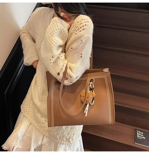 Brown litchi leather tote bag with white polka dots and bear pendant worn by model