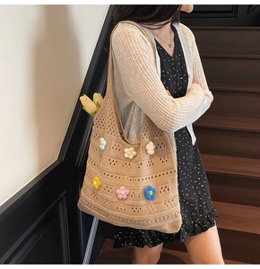 Detailed view of beige crochet tote bag with colorful 3D knitted flowers and soft texture