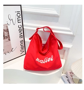Detail of red canvas hobo bag featuring white malivi script embroidery and adjustable strap