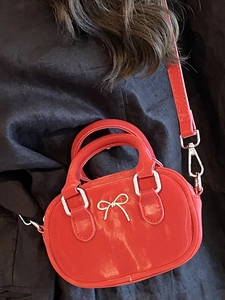 Glossy red mini bowling bag with metallic bow detail and detachable crossbody strap