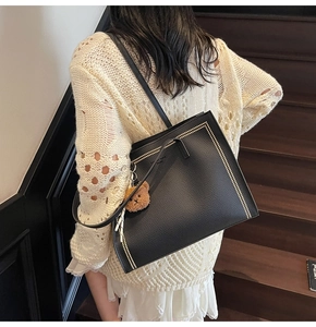 Litchi texture black tote bag with gold rivet edges and cute brown bear charm on shoulder