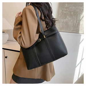 Detail view of black lychee grain leather tote bag with elegant gold metal hardware