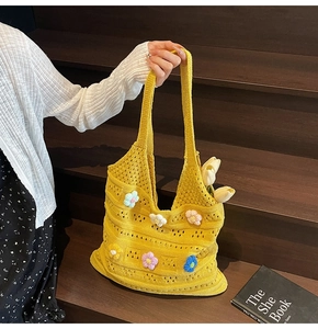 Detailed close-up of yellow knit tote bag with 3D floral accents on wooden stairs
