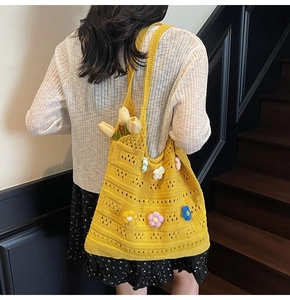 Detail of yellow knit tote bag featuring handcrafted colorful 3D crochet flowers