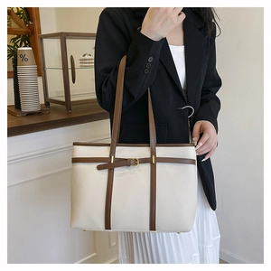 Detail of cream lychee texture tote bag with brown straps and vintage metal buckle