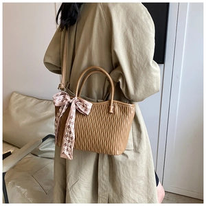 Detail of caramel tote bag with wavy pleats, arc handle and plaid silk scarf