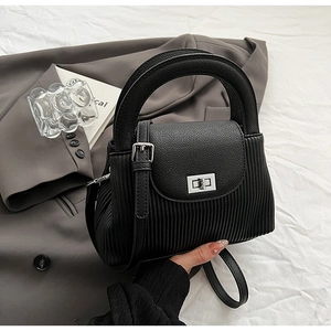 Detail of black crossbody bag with lychee pattern leather and silver metal twist lock