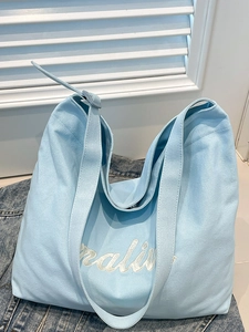 Minimalist light blue canvas tote bag with adjustable strap and stylish letter print