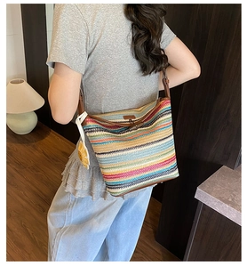 Detail view of colorful striped woven shoulder bag with cute sunflower charm accessory