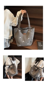 Detailed embroidery of small white dogs on a dark grey canvas tote bag for daily use