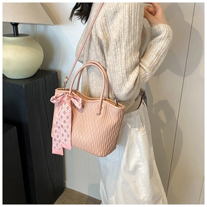 Detail of pink textured tote bag with decorative silk scarf and adjustable strap shown on model