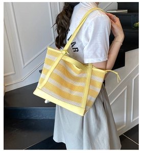 Detail of yellow and white striped mesh tote bag with drawstring on a model