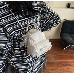 Détail du sac à dos en dentelle blanc crème avec chaîne de perles et nœud décoratif