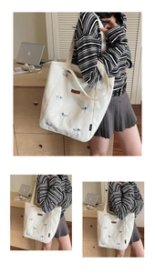 Close-up of cute dog embroidery details and brand label on cream canvas tote bag
