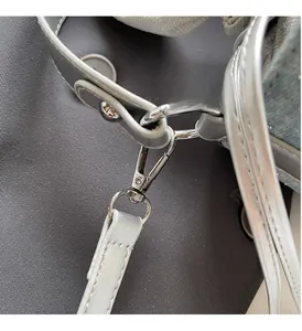 Détails des boucles métalliques argentées et ferrures sur le sac à bandoulière en denim