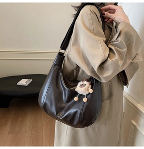 Dettaglio della borsa hobo in pelle opaca marrone scuro con ciondolo a forma di pecora