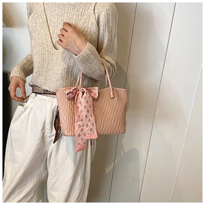 Pink wavy tote bag detail with luxury scarf tied to the handle on person shoulder