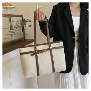 Detail of cream tote bag with lychee texture and brown straps on a model with blazer
