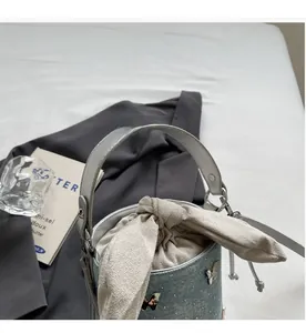 Détail du sac seau en jean bleu clair avec décor papillon et fermeture à cordon