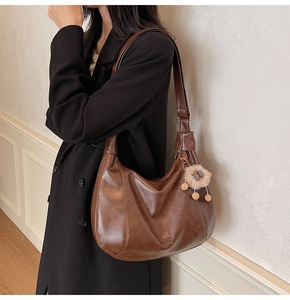 Dettaglio della borsa hobo marrone scuro vintage con un grazioso ciondolo a leoncino