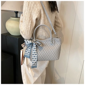 Detail of light blue pleated tote bag with a decorative plaid scarf on a model