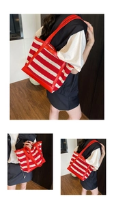 Red and white striped mesh tote bag with leather trim worn as an oversized shoulder bag