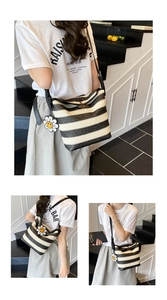 Detail view of woven straw shoulder bag with black stripes and daisy flower charm