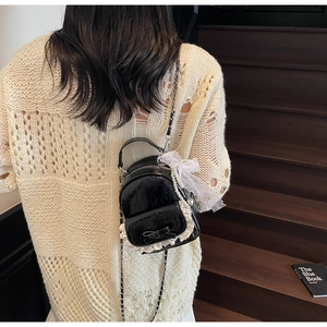 Détail d'un mini sac à dos noir brillant avec dentelle et perles sur chaîne