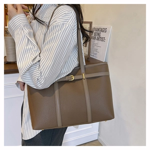 Detail of brown litchi pattern leather tote bag with gold buckle and long shoulder strap