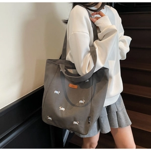 Detail of grey canvas tote bag featuring cute dog embroidery and wide shoulder strap