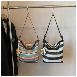 Close-up of woven straw tote bag with colorful stripes and decorative sunflower charm