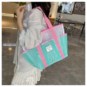 Detail of pink handle and mesh texture on a turquoise summer beach tote bag