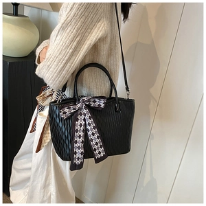 Detail view of black ripple textured tote bag with a stylish checkered bow scarf