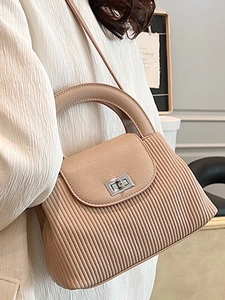 Minimalist beige pleated crossbody bag with silver twist lock shown on elegant model