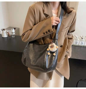 Vista dettagliata di una borsa tote in pelle nera con ciondolo a forma di orsetto bruno