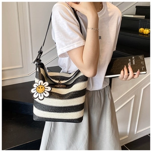 Close-up of woven tote bag with black and white stripes and smiling sunflower charm