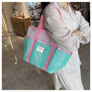 Detail view of a large mesh beach tote bag with pink handles and multiple pockets