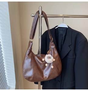 Dettaglio della borsa tote vintage marrone scuro con ciondolo a agnello su gruccia in metallo