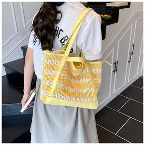 Close-up of yellow striped mesh tote bag with leather handles for summer travel