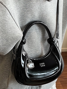 Fashionable black patent leather crescent handbag with silver chain and G charm