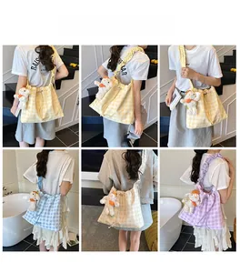 Detail of checkered drawstring tote bag with ruched strap and cute white puppy keychain