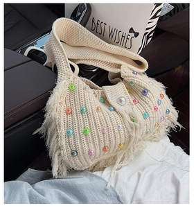 Détail du sac à bandoulière tissé crème avec perles colorées et franges dans une voiture