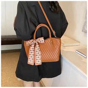Detailed close-up of brown textured tote bag with checkered ribbon and adjustable strap