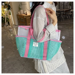 Detail of mint green and gray mesh beach bag with pink shoulder straps for summer travel