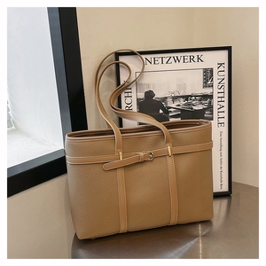 Detail showing litchi grain leather texture and belt buckle decor on khaki tote bag
