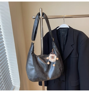 Dettaglio della borsa hobo in pelle retrò grigio scuro con logo dorato e ciondolo